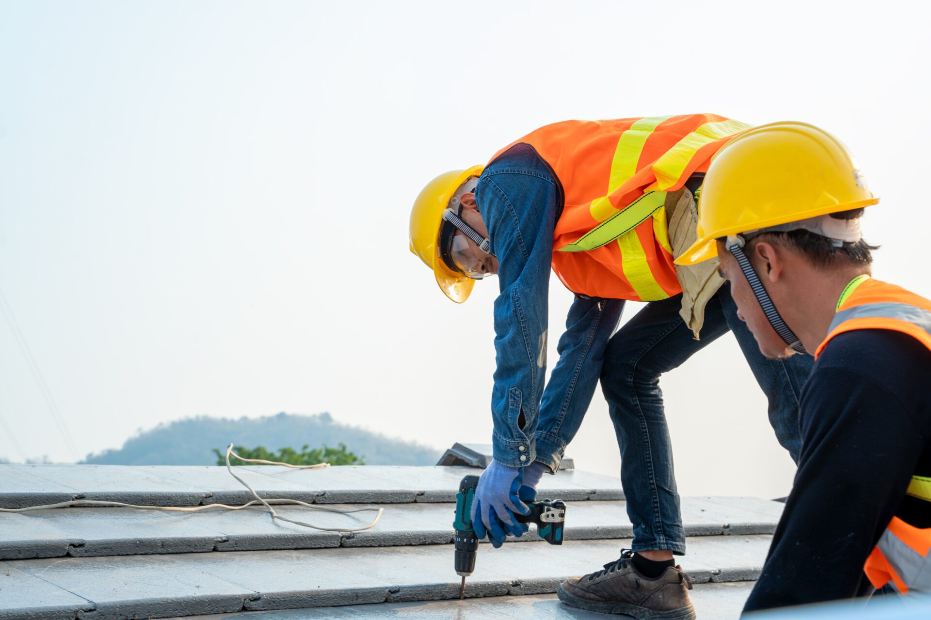 Roofer builder worker attach metal sheet to new roof on top roof